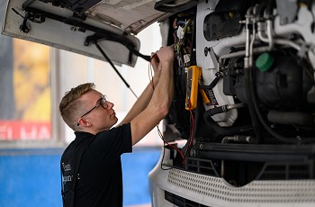 Ein Mitarbeiter prüft Elektrik an einem Mercedes-Benz LKW